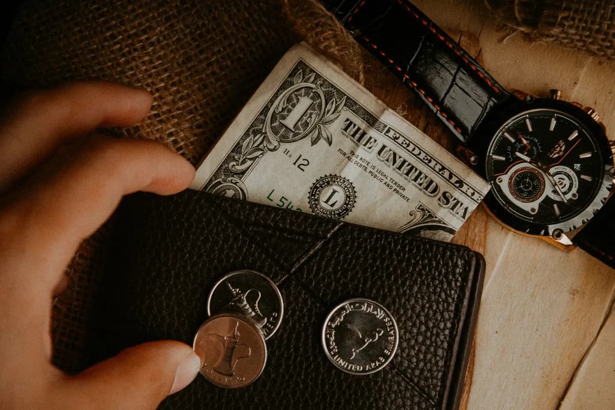 Leather wallet and watch arranged on a wooden surface